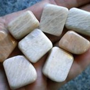 May include: A collection of eight white and peach-colored tumbled stones with a smooth, polished finish.
