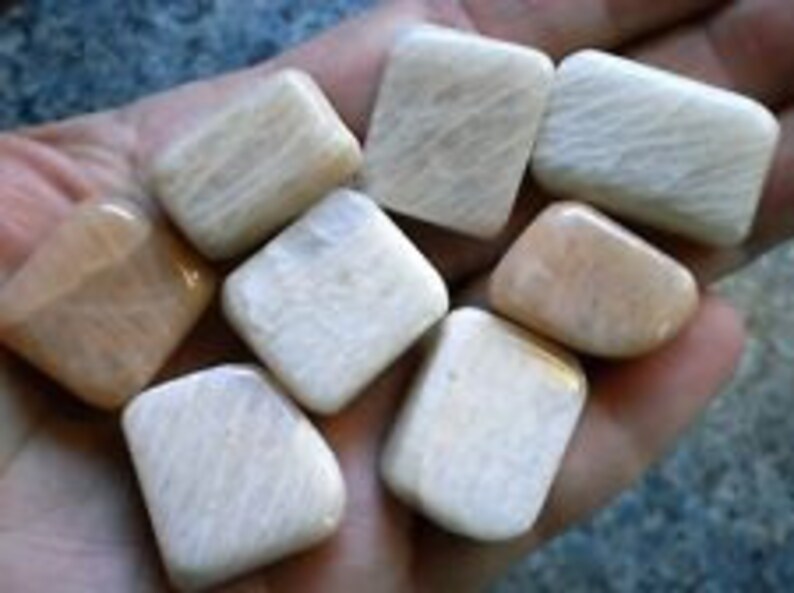 May include: A collection of eight white and peach-colored tumbled stones with a smooth, polished finish.
