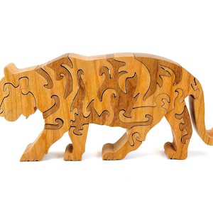 May include: A wooden tiger puzzle with interlocking pieces. The tiger is depicted in a walking pose, with detailed wood grain patterns. The puzzle is made of light and dark brown wood.