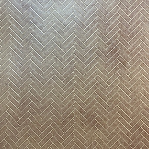 May include: A close-up view of a brown surface with a repeating herringbone pattern. The pattern is created with thin, light-colored lines that form a zig-zag design across the surface. The overall effect is a textured, geometric design.