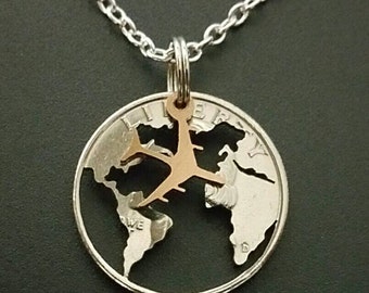 May include: A silver necklace with a silver quarter coin pendant featuring a cut-out world map with a gold airplane flying over it.