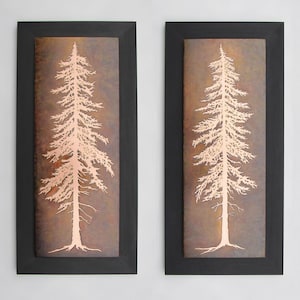 May include: Two framed wall art pieces with a copper background and a white silhouette of a pine tree in each frame. The frames are black.