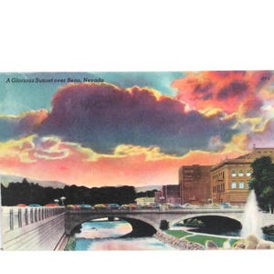 May include: Vintage postcard featuring a vibrant sunset over Reno, Nevada. The sky is filled with pink, orange, and purple hues. A bridge spans a river, with buildings and a fountain in the background. Text reads "A Glorious Sunset over Reno, Nevada."