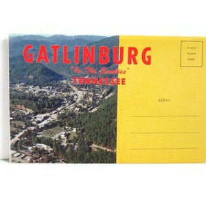 May include: Vintage postcard featuring an aerial view of Gatlinburg, Tennessee, with the text "GATLINBURG" in red. The postcard has a yellow back with space for a stamp and address. The image shows a town nestled in a valley surrounded by green trees and mountains.