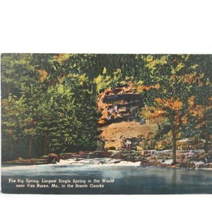 May include: A white ceramic mug with a black handle and the text "But First, Coffee" in a black, bold font. The mug is on a white surface.