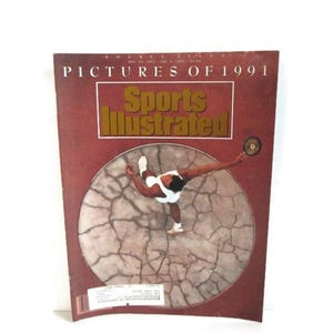 May include: A Sports Illustrated magazine cover titled Pictures of 1991, featuring a maroon background and a central circular graphic of an athlete throwing a discus on cracked earth. The text reads Double Issue, Dec 30, 1991-Jan 6, 1992, $3.95.