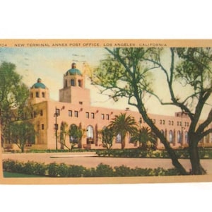 May include: Vintage postcard featuring the New Terminal Annex Post Office in Los Angeles, California. The image shows a large, beige building with multiple arched windows and two domed towers. Palm trees and other greenery are visible.