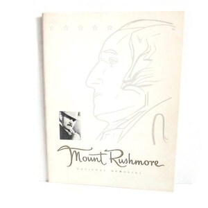 May include: A cream-colored brochure featuring a sketch of a profile of a man, with the text "Mount Rushmore National Memorial" in a script font. A small black and white photo is in the lower left corner, and three stars are at the top.