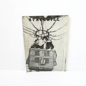 May include: A black and white vintage stagebill with the word "STAGEBILL" at the top. The image depicts two people in a hot air balloon basket. The balloon's design is visible above the basket.