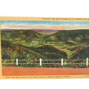 May include: A vintage postcard featuring a colorized landscape of The Devil's Saddle in West Virginia. The text reads W. VA. 20 - The Devil's Saddle, on U. S. Route 50, W. Va. and Back of this Gap to Right Nancy Hanks, Mother of Abraham Lincoln, was Born.