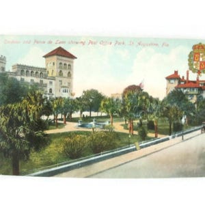 May include: Vintage postcard depicting the Ponce de Leon Hotel and Post Office Park in St. Augustine, Florida. The image shows a park with trees, a fountain, and buildings with red-tiled roofs. Text on the card reads "Cordova and Ponce de Leon showing Post Office Park, St. Augustine, Fla."
