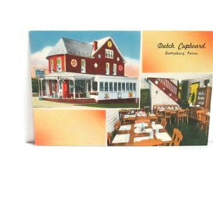 May include: Vintage postcard featuring the Dutch Cupboard restaurant in Gettysburg, Pennsylvania. The postcard shows a red building with white trim and a sign. The interior shows tables and chairs, and a staircase. The text "Dutch Cupboard" is printed on the postcard.
