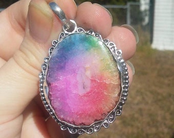 Peut inclure: Un pendentif en agate arc-en-ciel avec une monture en argent. L'agate est un magnifique mélange de rose, violet, bleu, vert et jaune.