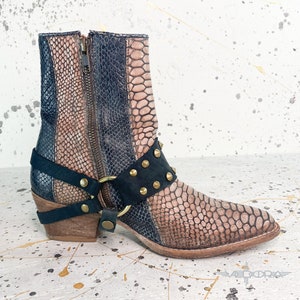 May include: Brown and black leather ankle boots with a snakeskin pattern and gold accents. The boots have a zipper on the side and a buckle strap with studs.