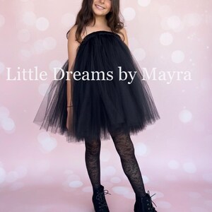 May include: A black strapless tulle dress with a gathered neckline and a voluminous skirt. The dress is paired with black patterned tights and black lace-up ankle boots. The text Little Dreams by Mayra is visible across the center of the image.