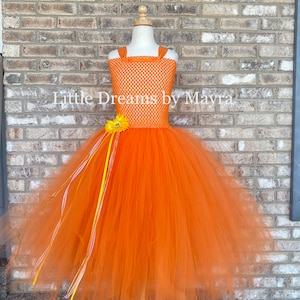 May include: Orange tulle tutu dress with a yellow flower and matching ribbons. The bodice is a white and orange mesh with a polka dot pattern. "Little Dreams by Mayra" is written on the dress.