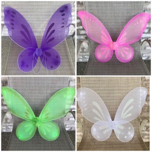 May include: Four pairs of butterfly wings in different colors: purple, pink, green, and white. The wings are made of sheer fabric and have a delicate, whimsical design.