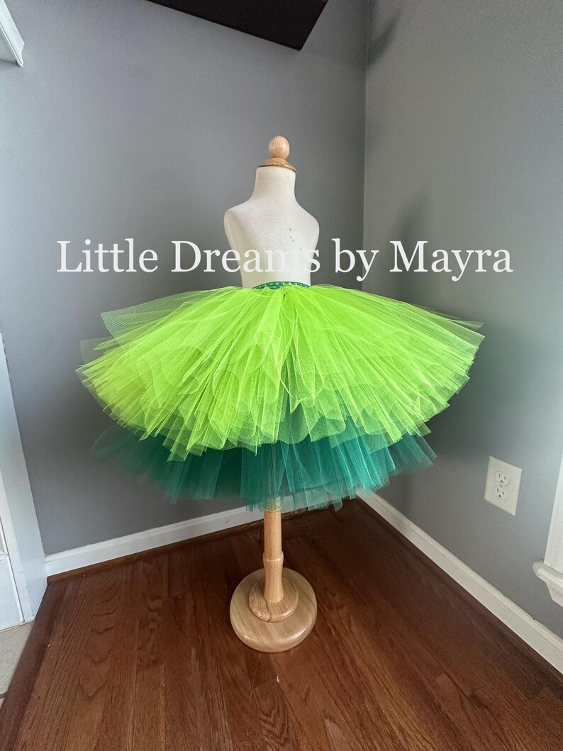 K&ouml;nnte beinhalten: Ein gr&uuml;ner und lindgr&uuml;ner T&uuml;ll-Tutu-Rock mit einem gr&uuml;nen elastischen Bund. Der Rock befindet sich auf einer wei&szlig;en Schaufensterpuppe. Der Text "Little Dreams by Mayra" ist im Bild sichtbar.