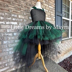 May include: A high-low dress featuring a black crocheted bodice with dark green velvet straps and a voluminous layered tulle skirt in alternating black and dark green colors. The text Little Dreams by Mayra is visible across the center.