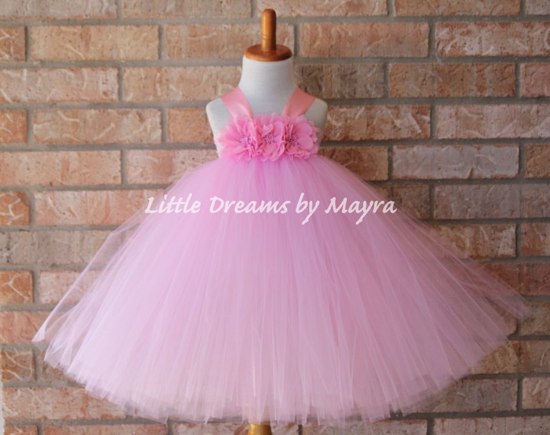 K&ouml;nnte beinhalten: Ein rosa T&uuml;ll-Tutu-Kleid mit einem rosa Satin-Oberteil und einer Blumenverzierung. Das Kleid befindet sich auf einer wei&szlig;en Kleiderpuppe. "Little Dreams by Mayra" steht auf dem Kleid.