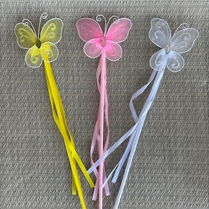 May include: Three butterfly wands with yellow, pink, and white butterfly wings and matching ribbons. The wands are made of white plastic and have a sparkly finish.