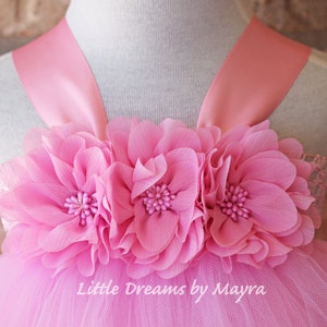 K&ouml;nnte beinhalten: Rosa T&uuml;ll-Tutu-Kleid mit einem rosa Satinband-Mieder und drei gro&szlig;en rosa Stoffblumen. Das Kleid hat den Text "Little Dreams by Mayra" auf dem Rock.