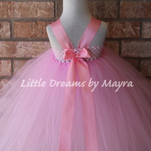 K&ouml;nnte beinhalten: Ein rosa T&uuml;ll-Tutu mit einer rosa Schleife aus Satinband und einem wei&szlig;en H&auml;kelbund. Das Tutu befindet sich auf einem Mannequin und der Text "Little Dreams by Mayra" ist auf dem Rock sichtbar.