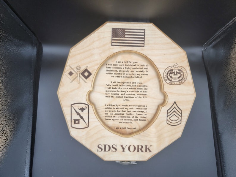 Puede incluir: Una placa octogonal de madera con una cita sobre ser sargento de instrucci&oacute;n en el ej&eacute;rcito de los Estados Unidos. La placa presenta la bandera estadounidense, un insignia militar y el texto "SDS YORK".