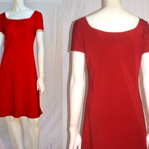 May include: A red dress with a square neckline and short sleeves. The dress has a white trim around the neckline and sleeves.
