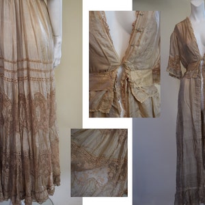 May include: A collection of vintage-style, light brown garments. The ensemble includes a long, tiered skirt with lace detailing, a flowing robe with lace trim, and a close-up of a bodice with delicate buttons and a tie closure. The fabrics appear sheer and lightweight.