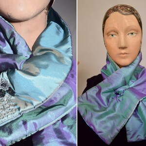 May include: A reversible scarf with a teal and purple iridescent fabric. One side features a beaded design.