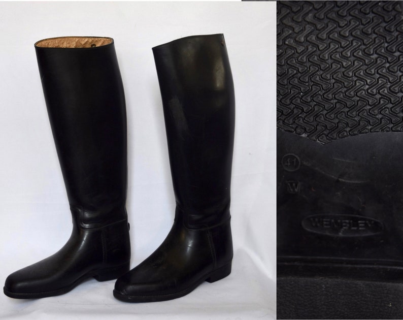 May include: A pair of black leather riding boots with a zipper on the back of the boot. The boots have a textured sole with the word "Wembley" on the bottom.