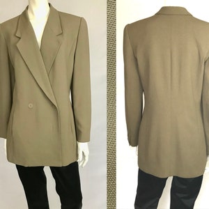 Puede incluir: Una chaqueta larga de doble botonadura en un color verde oliva apagado. La chaqueta tiene un corte clásico y entallado y se cierra con un solo botón en la parte delantera.