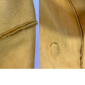 May include: Close-up of tan leather material. The left side shows a seam with a contrasting brown edge. The right side displays a stitched detail and a small, irregular mark, suggesting a natural texture or imperfection.