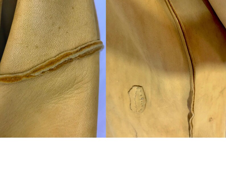 May include: Close-up of tan leather material. The left side shows a seam with a contrasting brown edge. The right side displays a stitched detail and a small, irregular mark, suggesting a natural texture or imperfection.