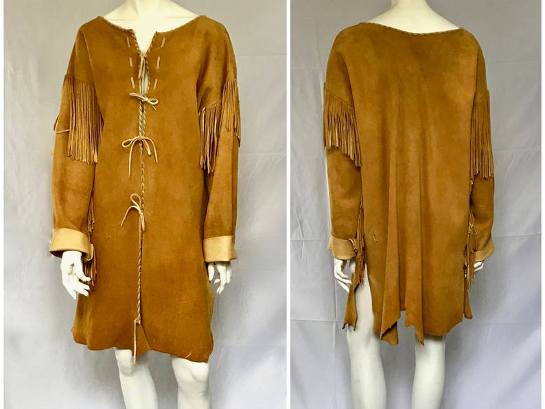 May include: A tan suede coat with long sleeves, fringe detailing on the sleeves, and a braided tie closure down the front. The coat has a V-neckline and tan cuffs. The coat is knee-length.