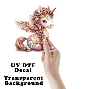 May include: A whimsical unicorn decal with a patchwork design in pastel colors. The unicorn has a golden horn, braided hair, and wings. The text "UV DTF Decal Transparent Background" is printed below the image.