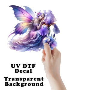 May include: A UV DTF decal with a transparent background featuring a fairy with purple and blue wings, a flowing gown, and a large iris flower. The fairy is resting her head on the flower. The text "UV DTF Decal" and "Transparent Background" are visible.