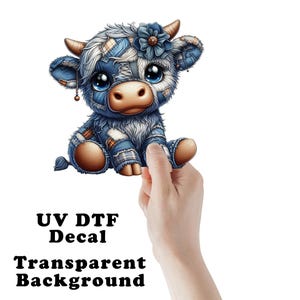 May include: A cute, cartoon-style cow decal with a patchwork denim design. The cow has large blue eyes, a flower on its head, and small horns. The text "UV DTF Decal Transparent Background" is printed below the cow.