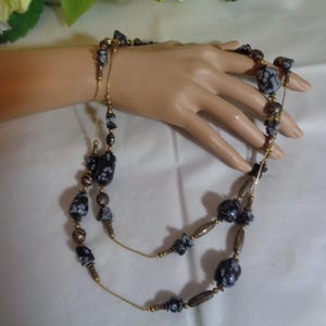 May include: A double-strand necklace with black and white patterned beads and gold accents.