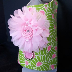 May include: A green and pink floral dog harness with a pink flower embellishment and a silver D-ring.