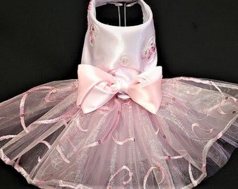 May include: A pink tulle tutu dog dress with a satin bow and pink embroidery.