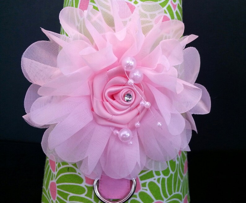 May include: A pink flower with a pearl and rhinestone embellishment, attached to a green and pink patterned fabric.