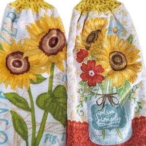 Puede incluir: Dos toallas de cocina de crochet amarillo con botones de madera. Una toalla presenta un dise&ntilde;o de girasol con el texto "Fig. 1", la otra presenta un dise&ntilde;o de girasol y flor roja con un tarro de cristal azul.