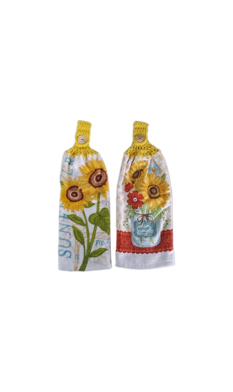 Puede incluir: Dos toallas de cocina de crochet amarillo con dise&ntilde;os de girasoles. Una toalla presenta un solo girasol con el texto "Summer" y "Fig. I." La otra toalla presenta un ramo de girasoles en un frasco de vidrio con flores rojas y naranjas.