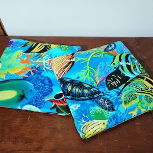May include: Two blue cushion covers featuring a colourful tropical fish and coral reef design.