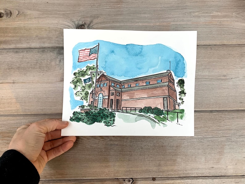 May include: Watercolor painting of a brick building with a flagpole and an American flag. The building has a brown roof and windows. There are trees and bushes in the foreground.