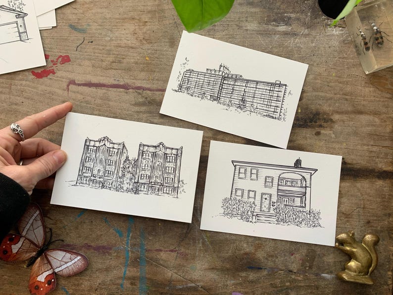 May include: Three black and white line drawings of buildings on white card stock. The first drawing shows a two-story building with a flat roof. The second drawing shows a three-story building with a flat roof. The third drawing shows a one-story building with a pitched roof.