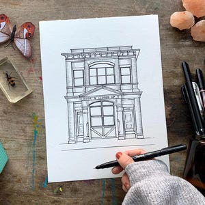 May include: Black and white line drawing of a building with the text "Hook & Ladder No. 5" above the entrance. The building has a large garage door and two windows on each side.