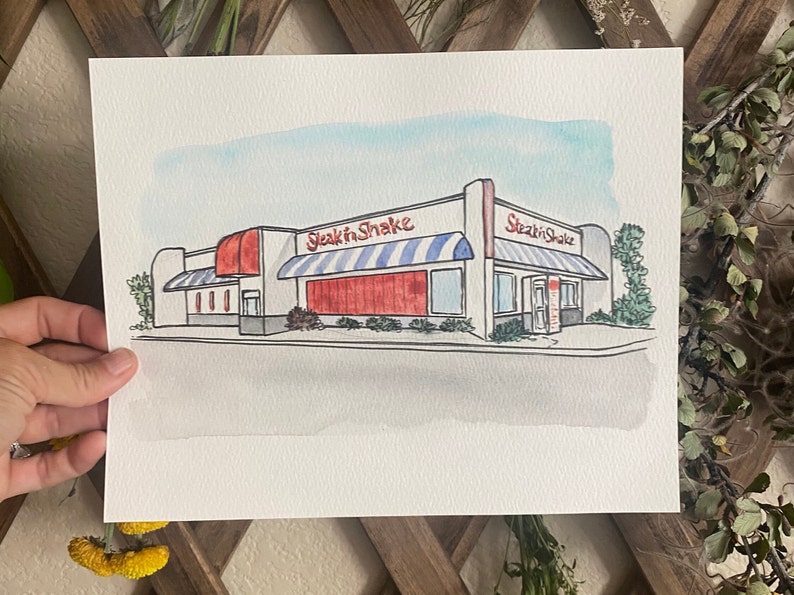 Custom artwork shows an image of a restaurant on 8x10” watercolor paper. The watercolor painting sits in the middle of the paper, with a 2-3 inch white border that allows for nice matting and framing.